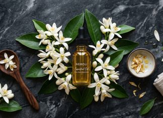 Neroli Essential Oil: 10 Proven Benefits for Skin, Mood and Wellbeing Neroli essential oil bottle surrounded by fresh white orange blossoms on dark marble