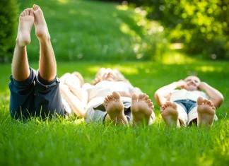 The Healing Benefits of Earthing Family lying barefoot on lush green grass practicing grounding and earthing therapy outdoors
