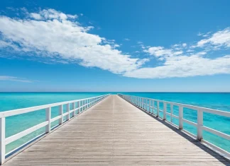 Ways To Set Your Goals You’ll Actually Achieve Wooden boardwalk pier stretching forward towards calm turquoise sea symbolizing clear path to achieving goals