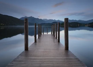 How Death Teaches Us to Live Fully Tranquil wooden dock extending into serene misty lake reflecting distant mountains